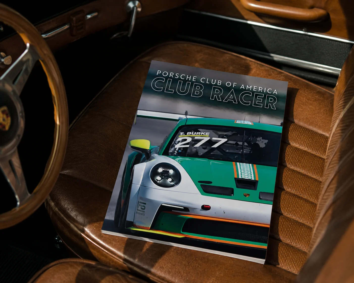 Porsche Club of America Club Racer June 2026 cover featuring a blue Porsche Cayman GT4 race car in pit lane.