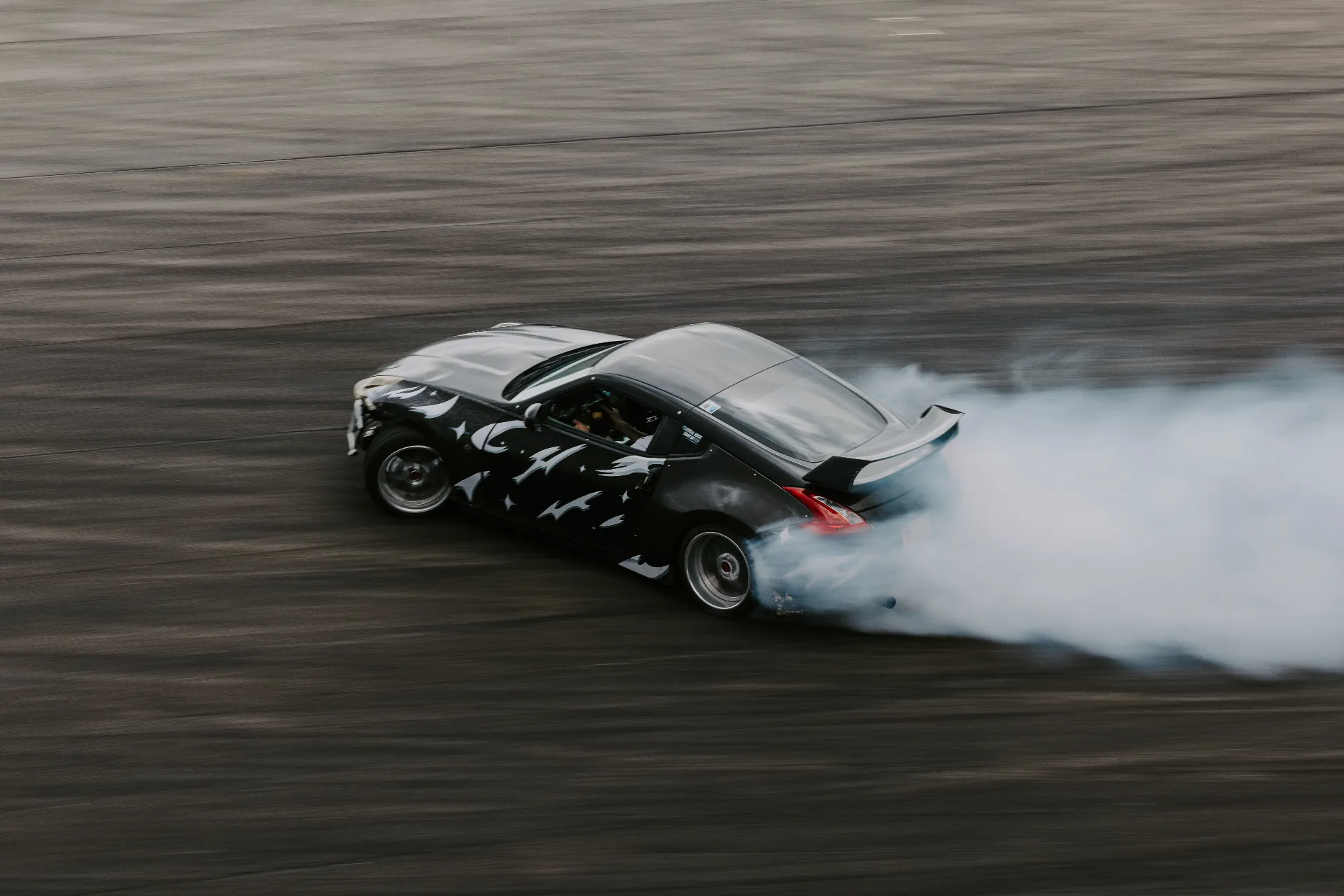 Nissan 370Z drift car initiating a slide on a sunlit Salt Lake City circuit.
