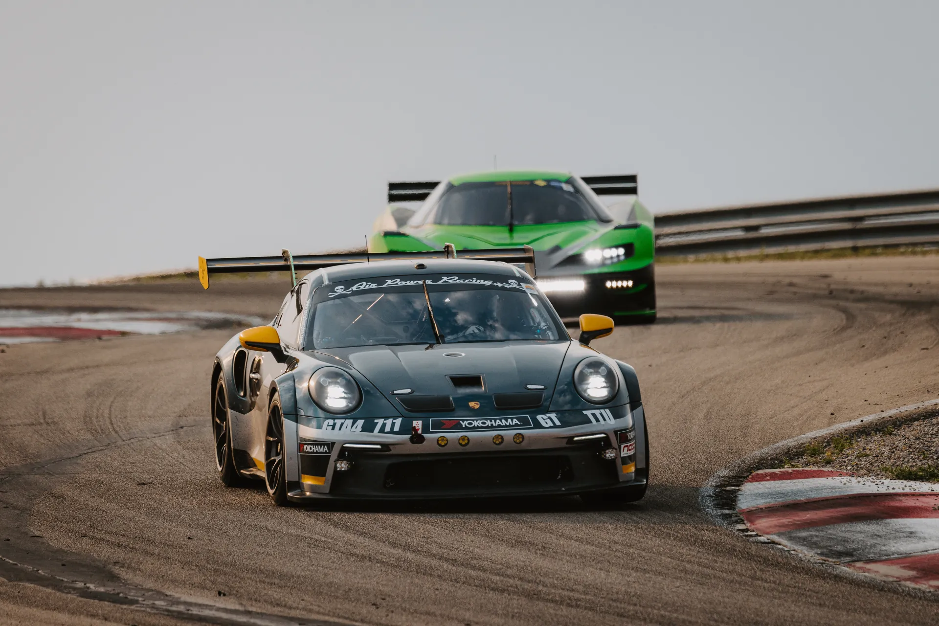 Porsche GT4 race car on track during a NASA endurance event, captured mid-corner with motion blur.