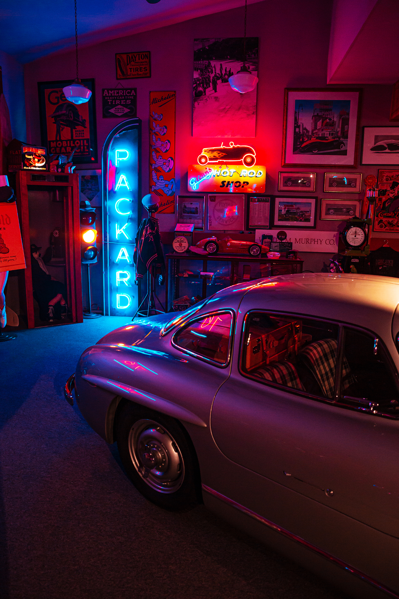 Interior of Glenn's Hot Rod Shop with a classic hot rod under work lights and vintage tools.