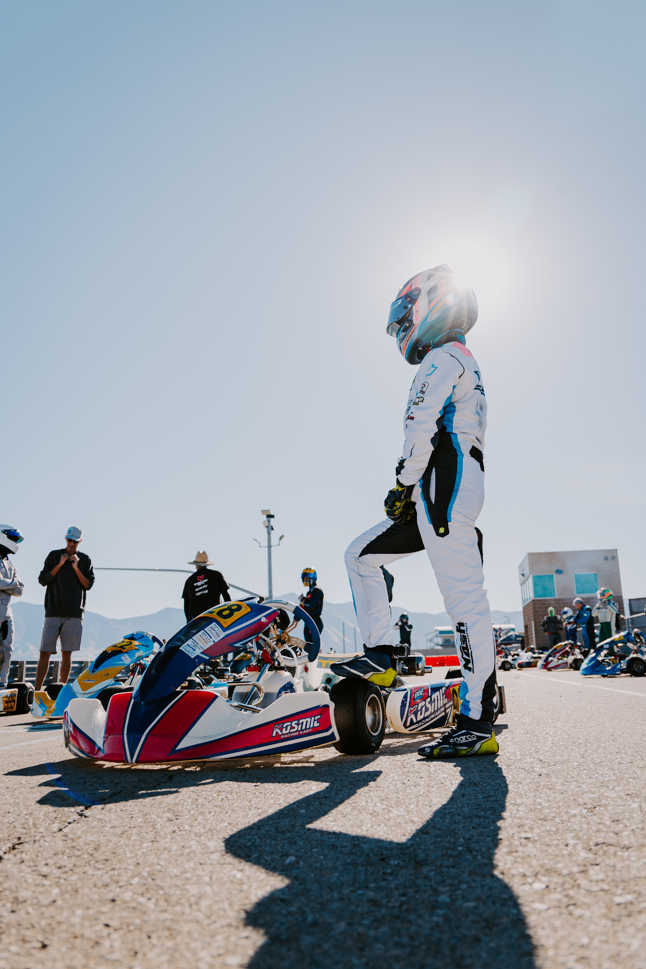Portrait of a karting driver standing on the grid in full race suit before the green flag.