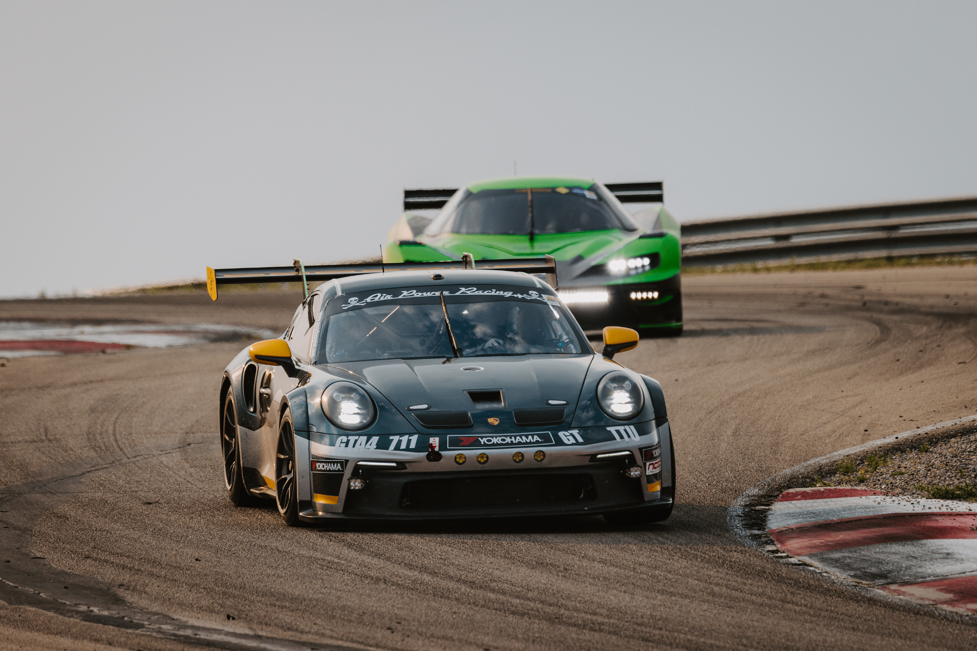 Porsche GT4 race car on track during a NASA endurance event, captured mid-corner with motion blur.