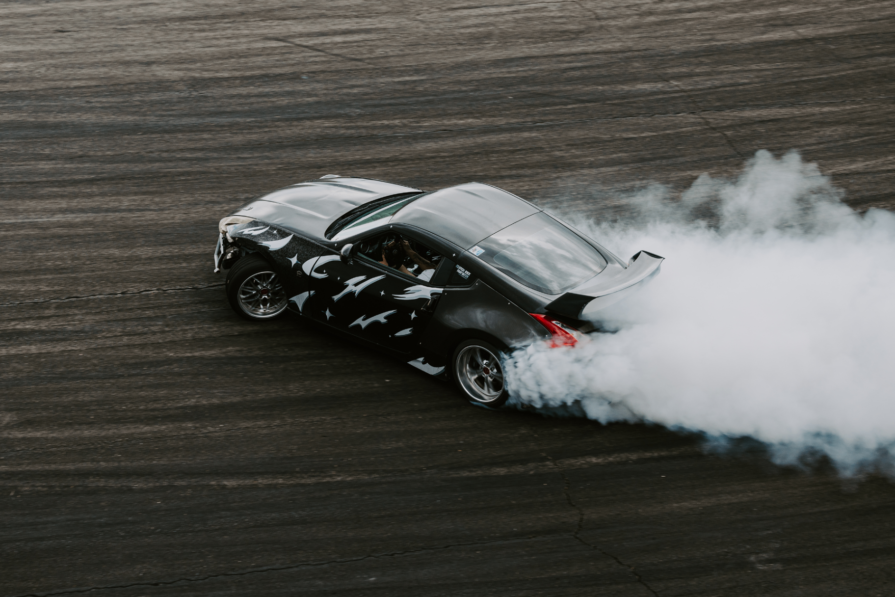 Nissan 370Z drift car engulfed in white tire smoke at a Salt Lake City drift event.
